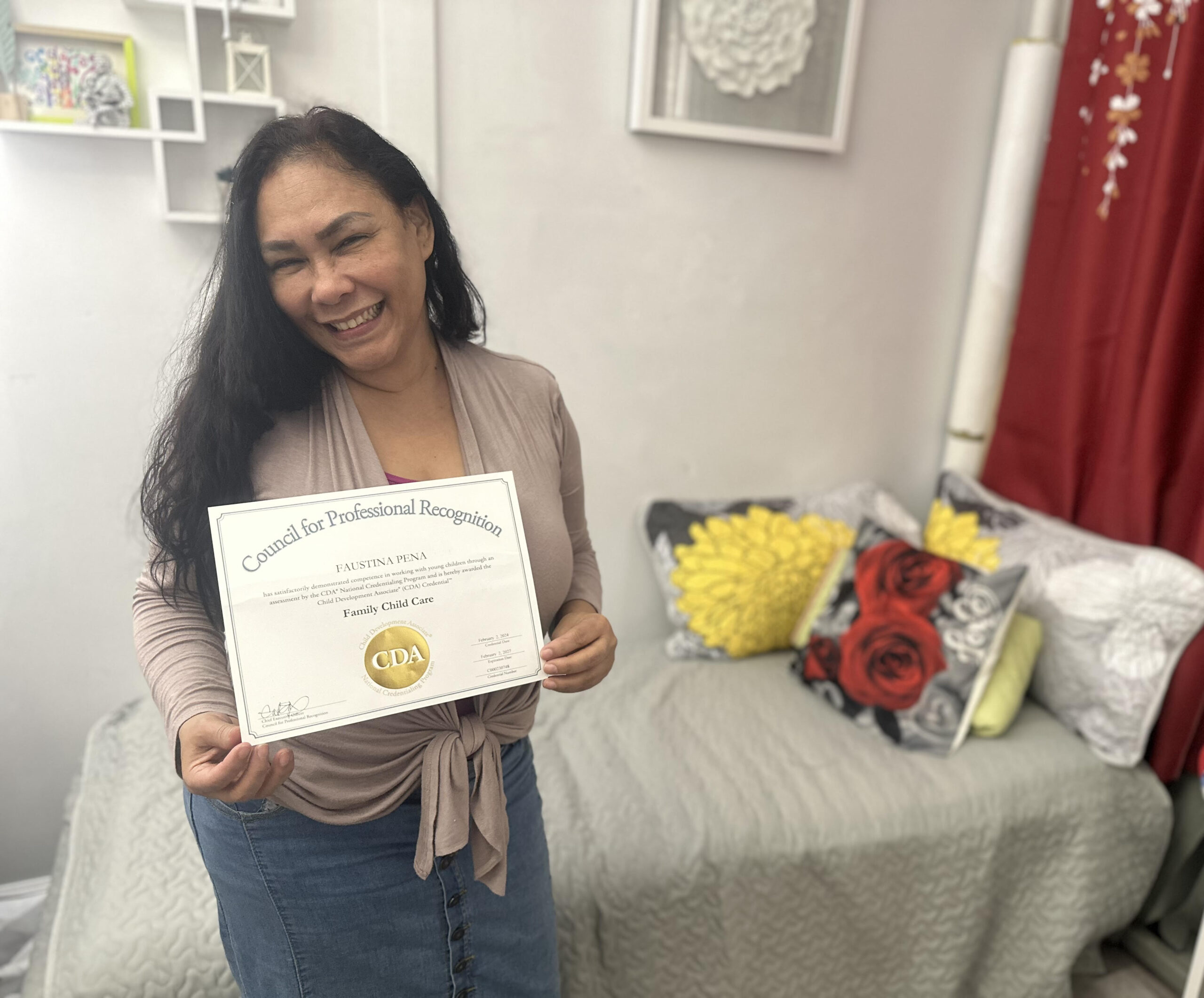 A woman proudly holding a certificate with flowers nearby.